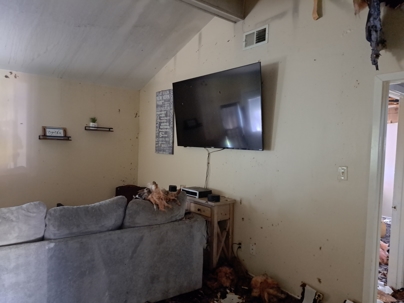 A bedroom with visible water damage coming from the roof into the walls.
